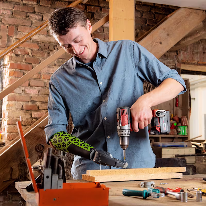 A man with a Greifer prosthetic hand from Ottobock using a drill.