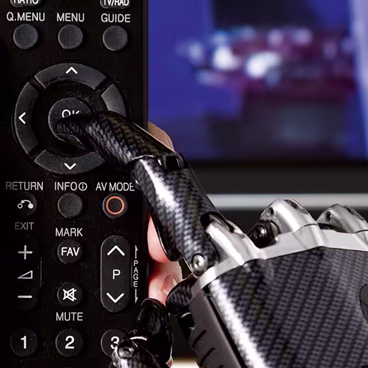 Zu sehen ist eine Fernbedienung, die von einer Prothetik Hand umfasst wird.