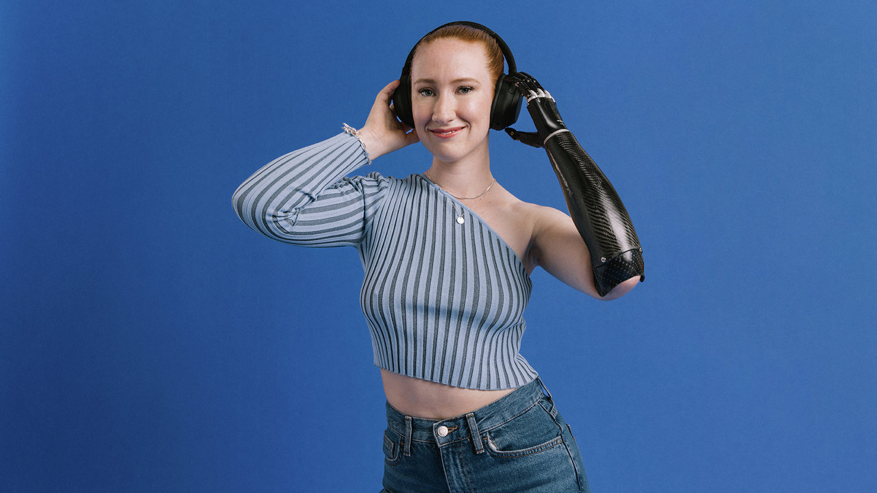 Eine Armprothesenträgerin hört Musik und hält Ihre Hände an den Kopfhörern. Sie trägt die bebionic Hand von Ottobock. 