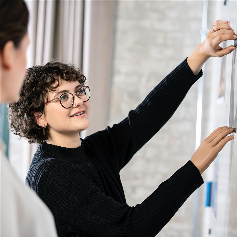 Lina using her Ottobock bebionic hand to hang a poster on the wall.