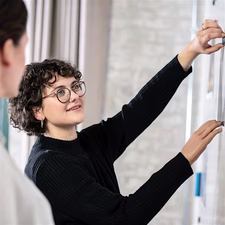 Lina using her Ottobock bebionic hand to hang a poster on the wall.