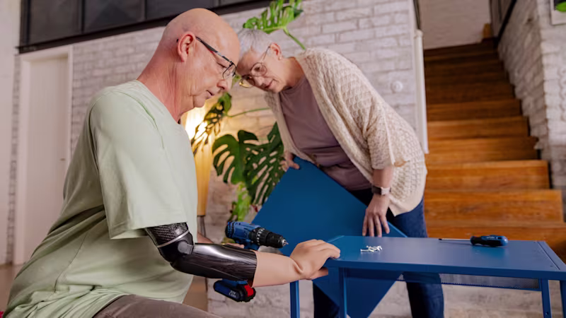 Ralf using the Speedhand myoelectric prosthetic hand while building a table, demonstrating its precision and functionality in woodworking.