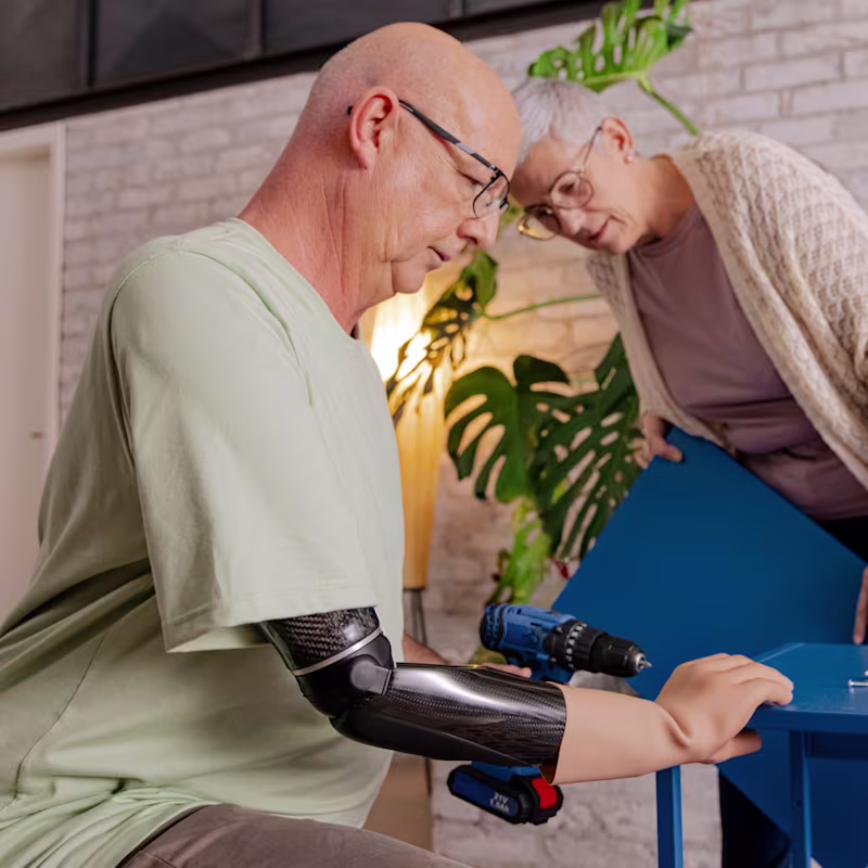 Ralf using the Speedhand myoelectric prosthetic hand while building a table, demonstrating its precision and functionality in woodworking.