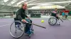 Ein Mann, der im Rollstuhl sitzt, schlägt bei einem Sportwettbewerb einen Tennisball mit einem Tennisschläger 