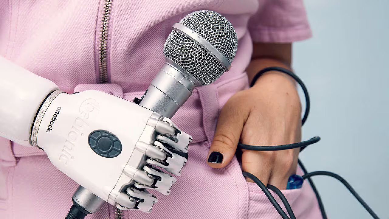Eine Armprothesenträgerin hält ein Mikrofon in Ihrer rechten Hand. Sie trägt die bebionic Hand von Ottobock.