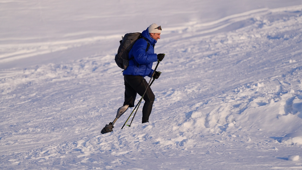 Mężczyzna z protezą nogi Genium X4 wspina się po ośnieżonym, górskim zboczu