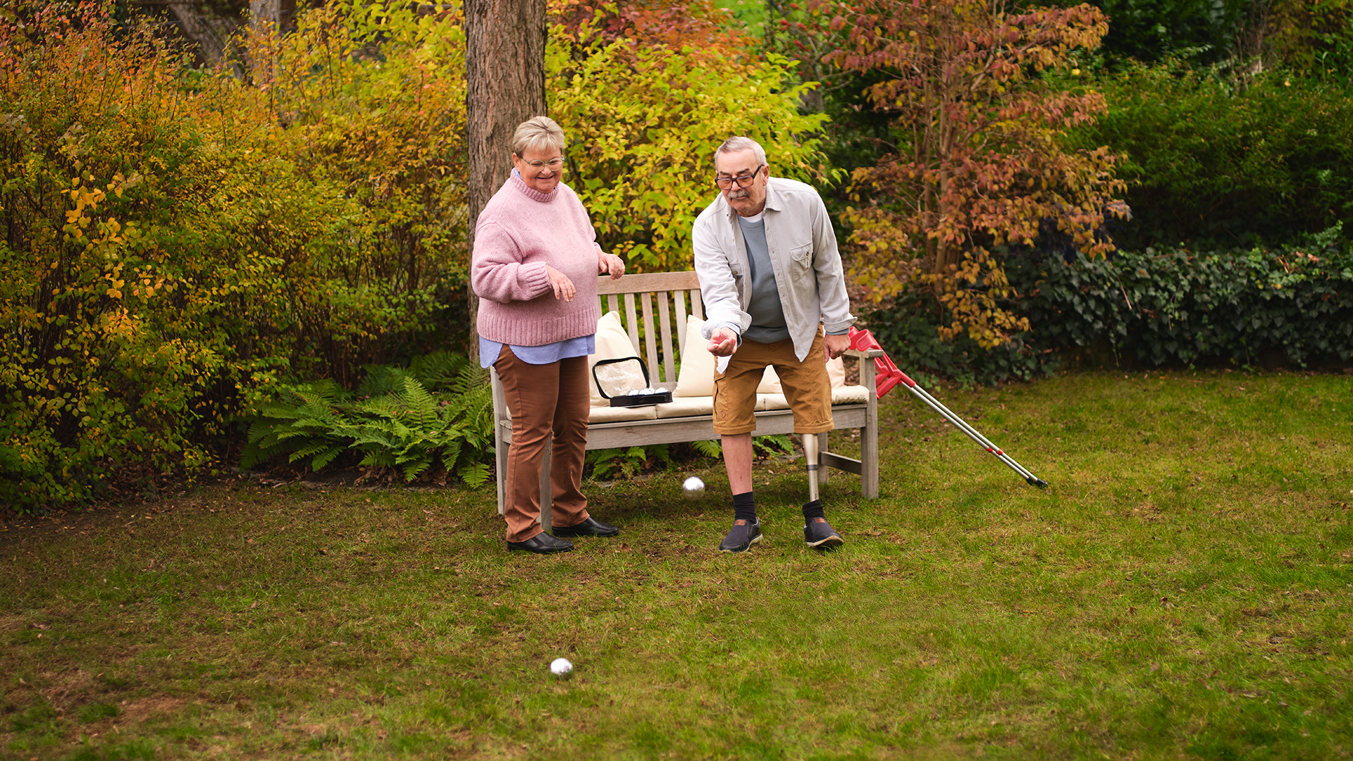 Ein älteres Paar spielt gemeinsam im Garten Boule. Der Mann trägt dabei das mechatronische Kniegelenk Kenevo von Ottobock.