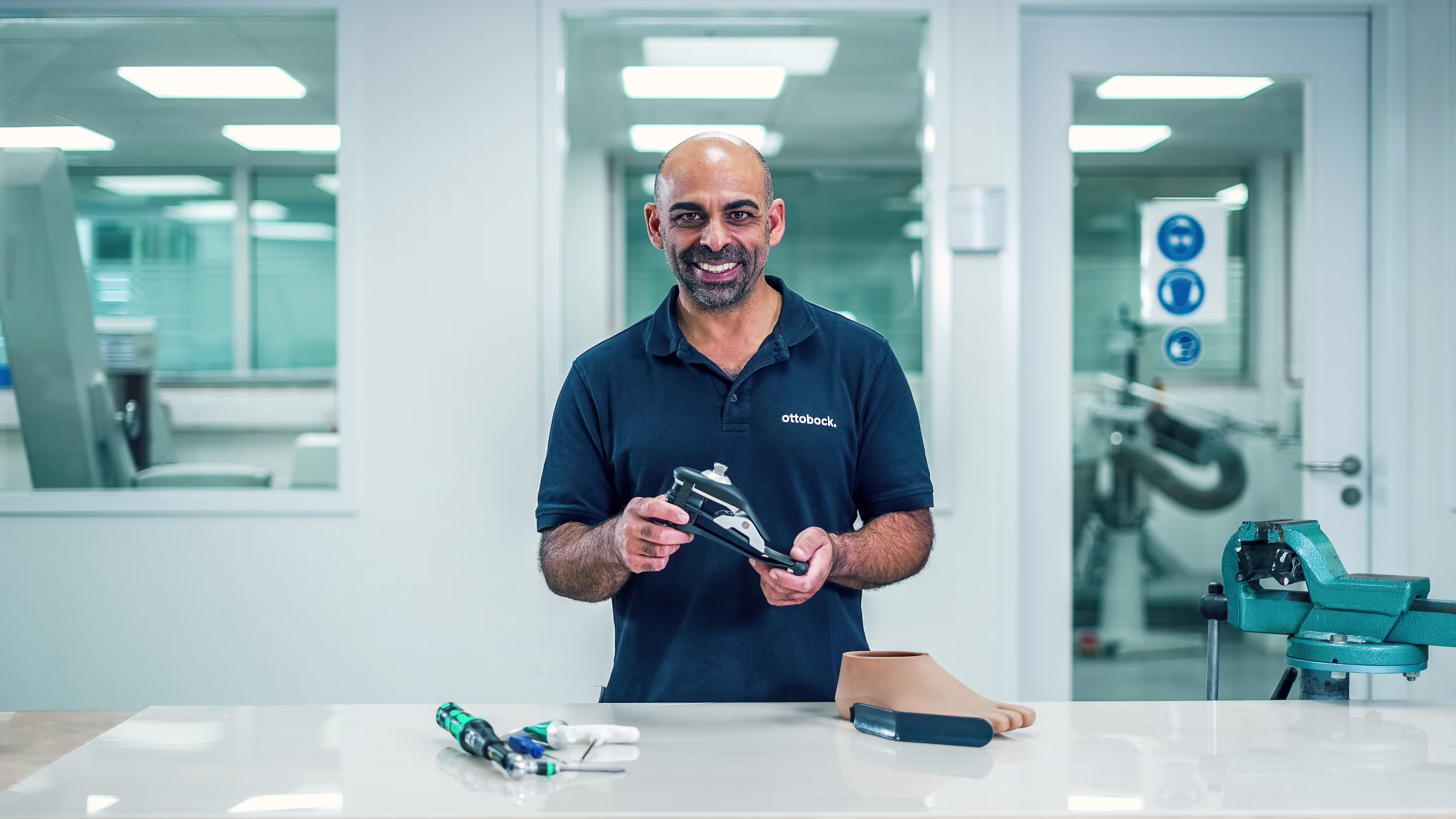 Un técnico protésico sosteniendo un pie artificial por Ottobock en una estación de trabajo