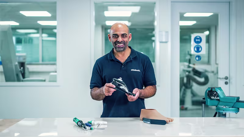 Un técnico protésico sosteniendo un pie artificial por Ottobock en una estación de trabajo
