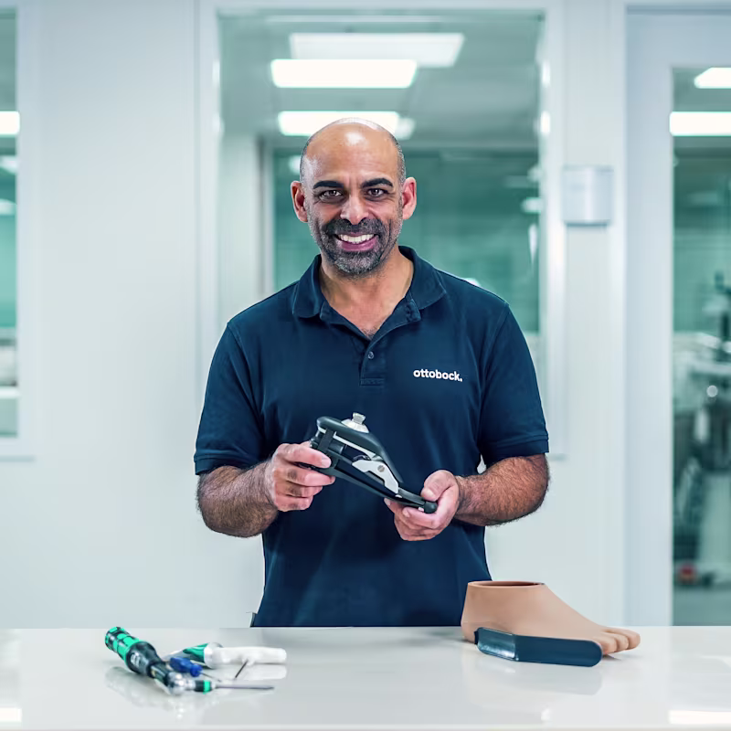 A Prosthetic Technician holding a artificial foot by Ottobock at a work station