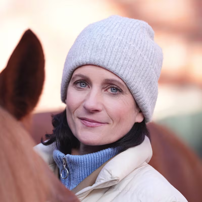 Siglind steht mit Ihrem Pferd vor Ihrem Pferdestall. Sie trägt das mechatronische Prothesenkniegelenk Genium X4 von Ottobock.