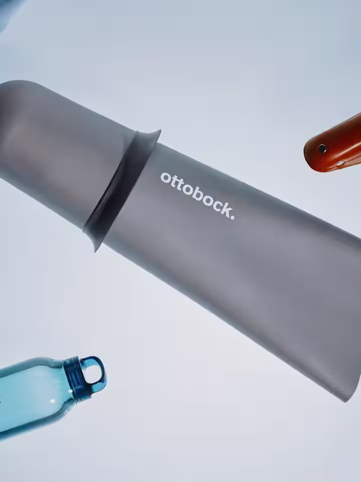 Przedmioty leżące na stole: liner do protezy, siodełko na rower, butelka na wodę, okulary.