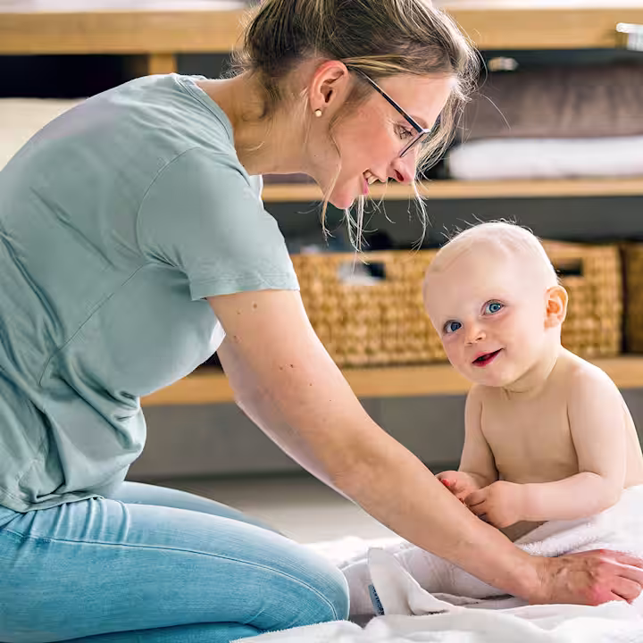 Baby and its mother sitting on the floor smiling