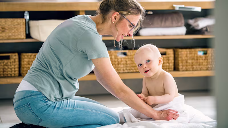 Baby and its mother sitting on the floor smiling