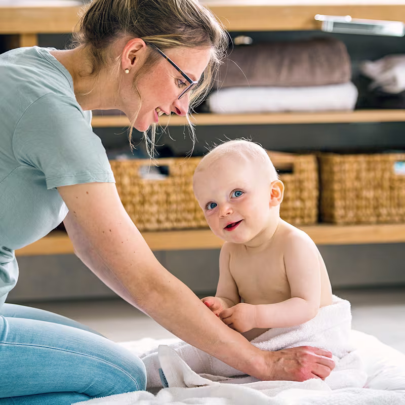 Baby and its mother sitting on the floor smiling