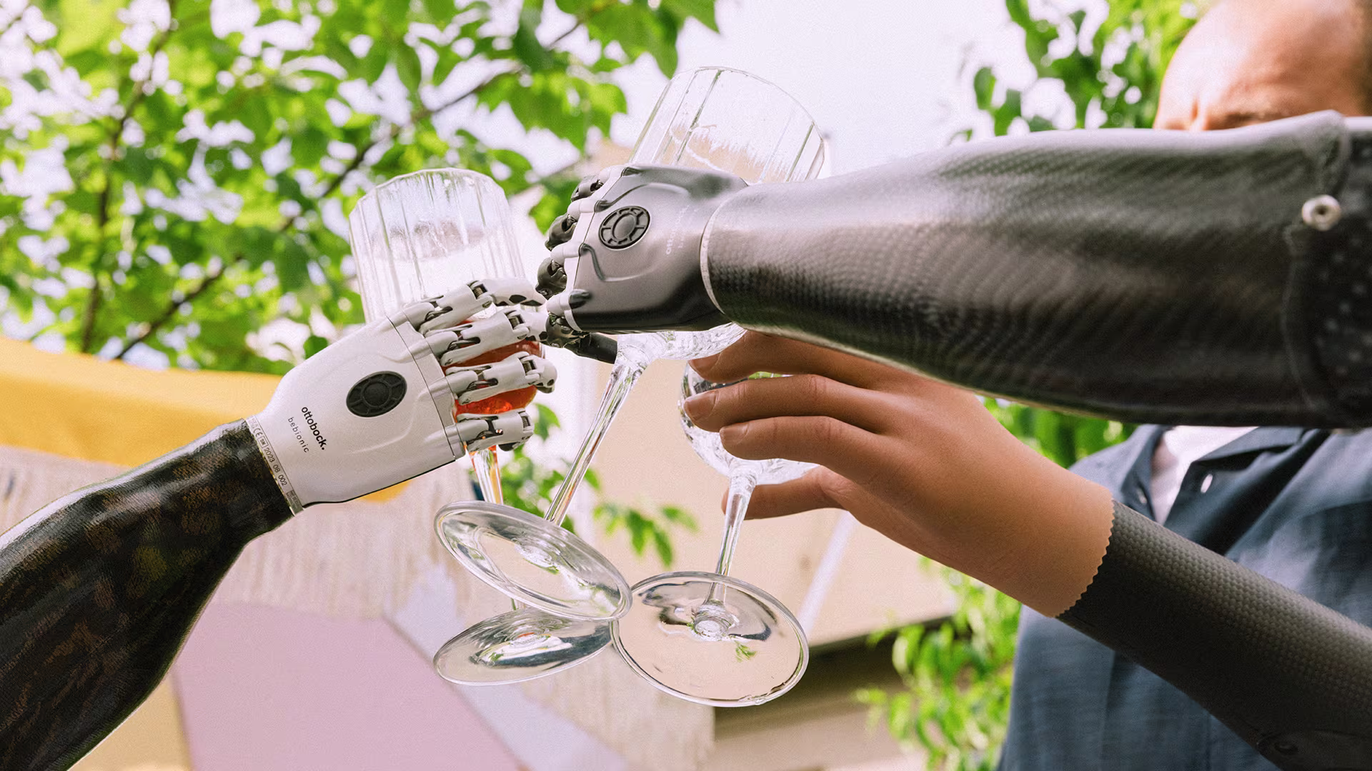 Ottobock prosthetic arm users, wearing bebionic hand and Speed Hand, toasting.