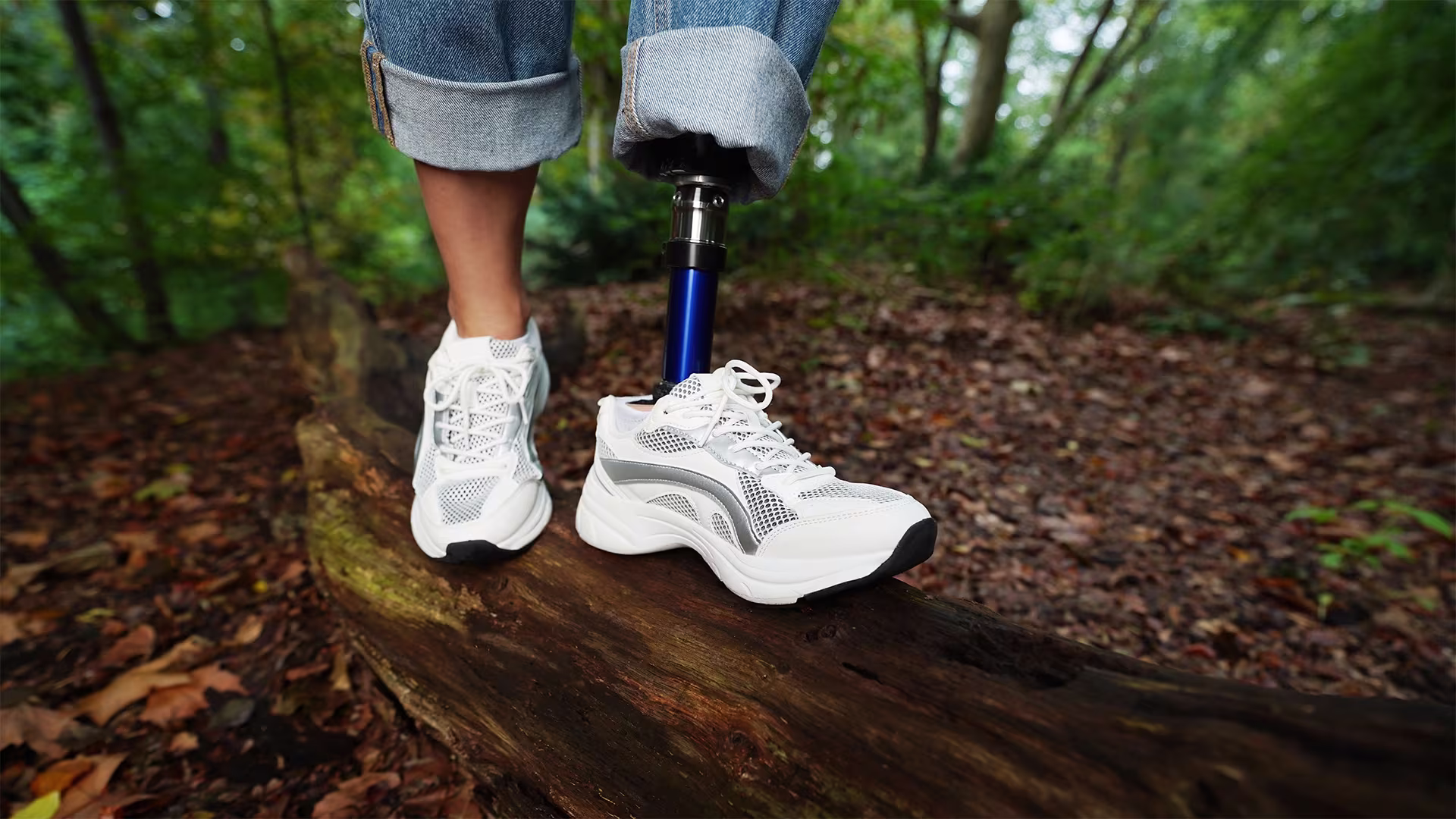 A women wearing white shoes and the Ottobock Evanto prosthetic foot walking along a fallen tree trunk