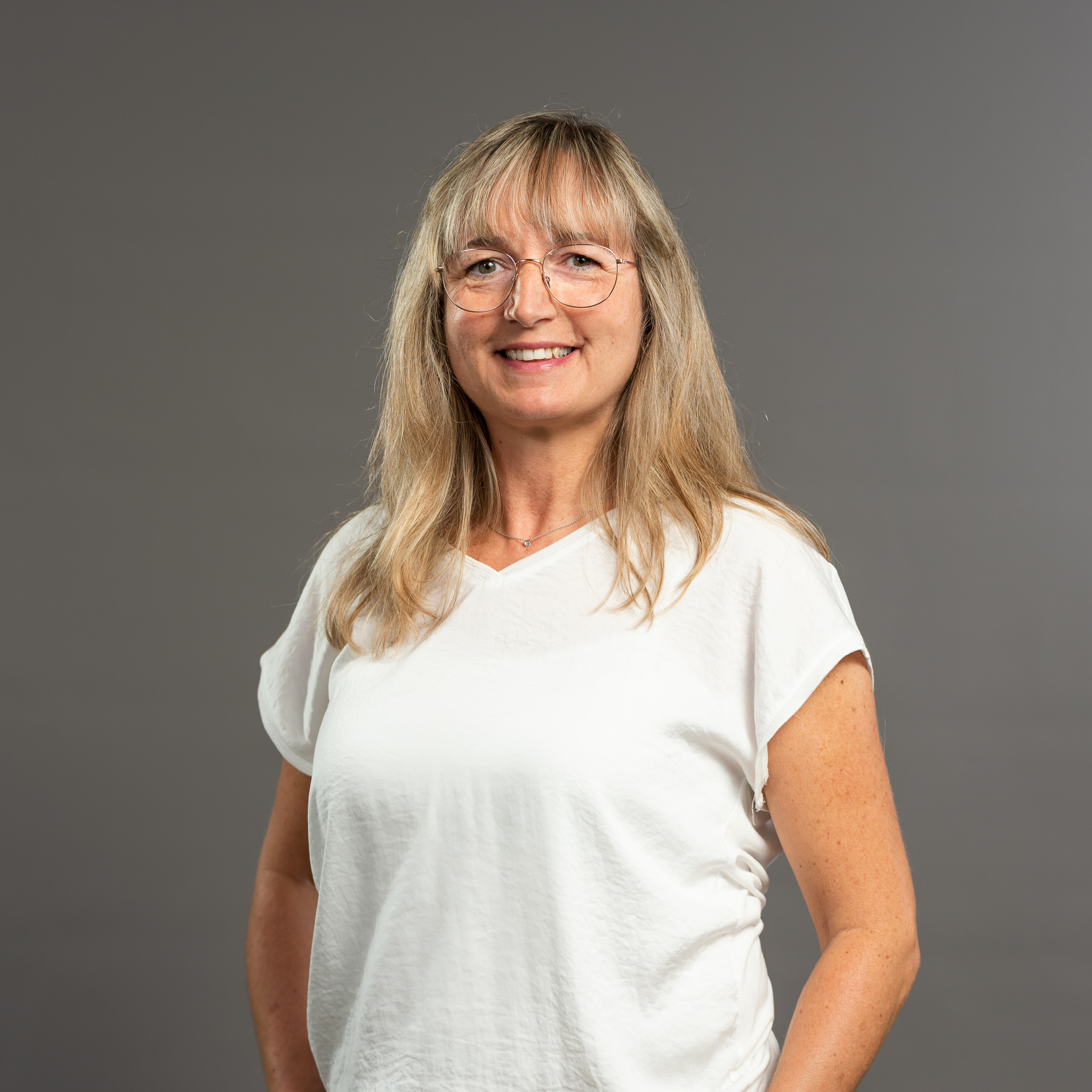 Auf dem Bild ist das Portrait einer Ottobock Academy Mitarbeiterin zu sehen. Sie hat blonde lange Haare, trägt eine Brille und lacht in die Kamera.