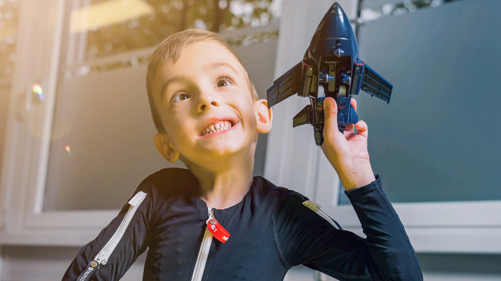 Boy in an Exopulse Mollii Suit from Ottobock playing with a toy plane. 