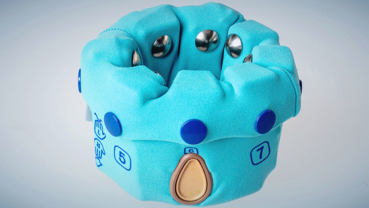 A picture of Ottobock's myosmart cuff on a bright white background. A teal, cloth-covered device made to fit around the arm with metallic circles that touch the patient's skin to measure myoelectric signals