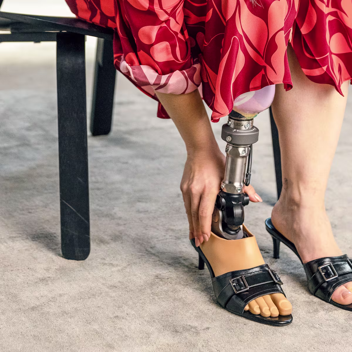 A female user is sitting on a chair with her Taleo Adjust foot.
