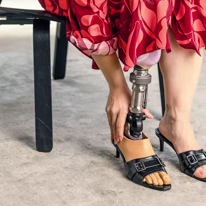 A female user is sitting on a chair with her Taleo Adjust foot.