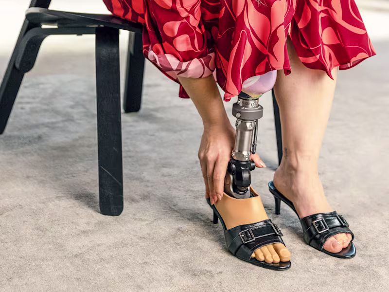 A female user is sitting on a chair with her Taleo Adjust foot.