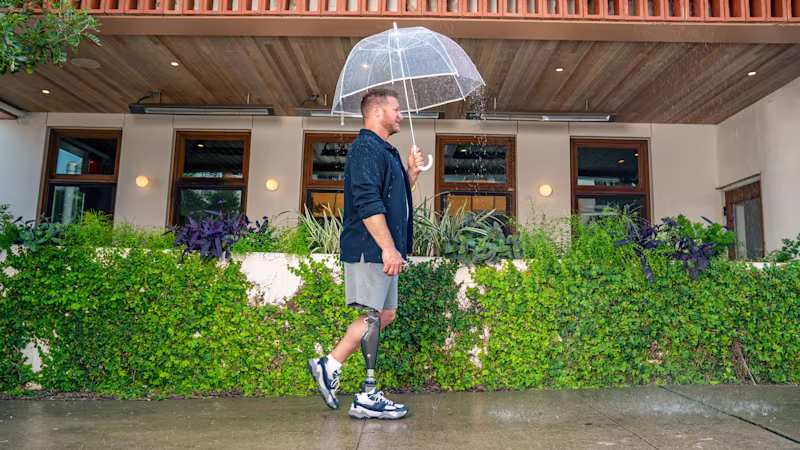 An amputee wearing his Ottobock C-Leg 4 while walking in the rain with his umbrella.
