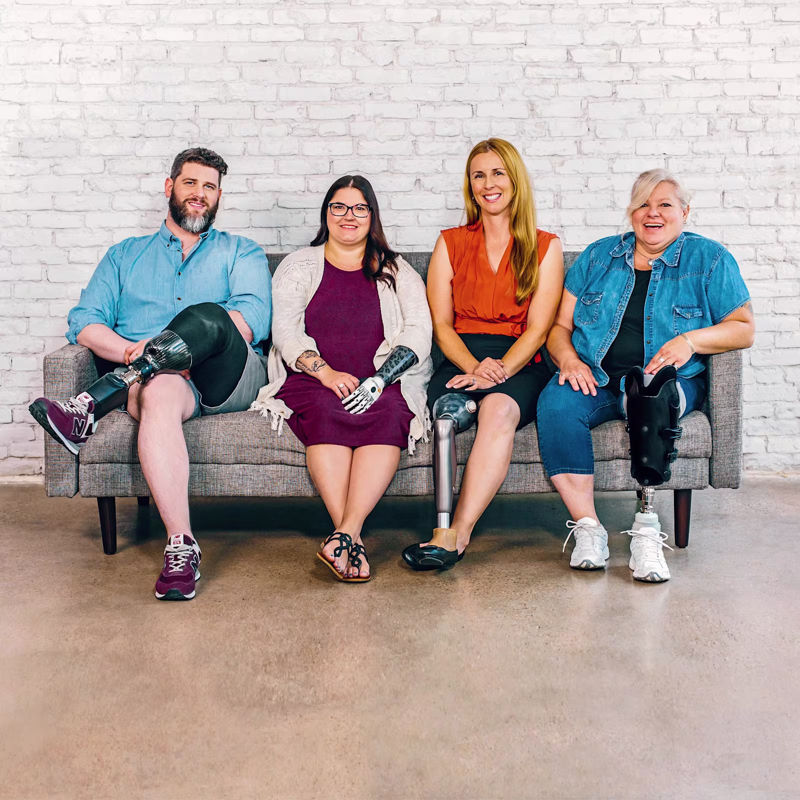 Quattro persone sedute su una panchina. Un uomo con una protesi alla gamba sotto il ginocchio, una donna con una mano bionica, una donna con una protesi al ginocchio C-Leg e una donna con una protesi transtibiale.