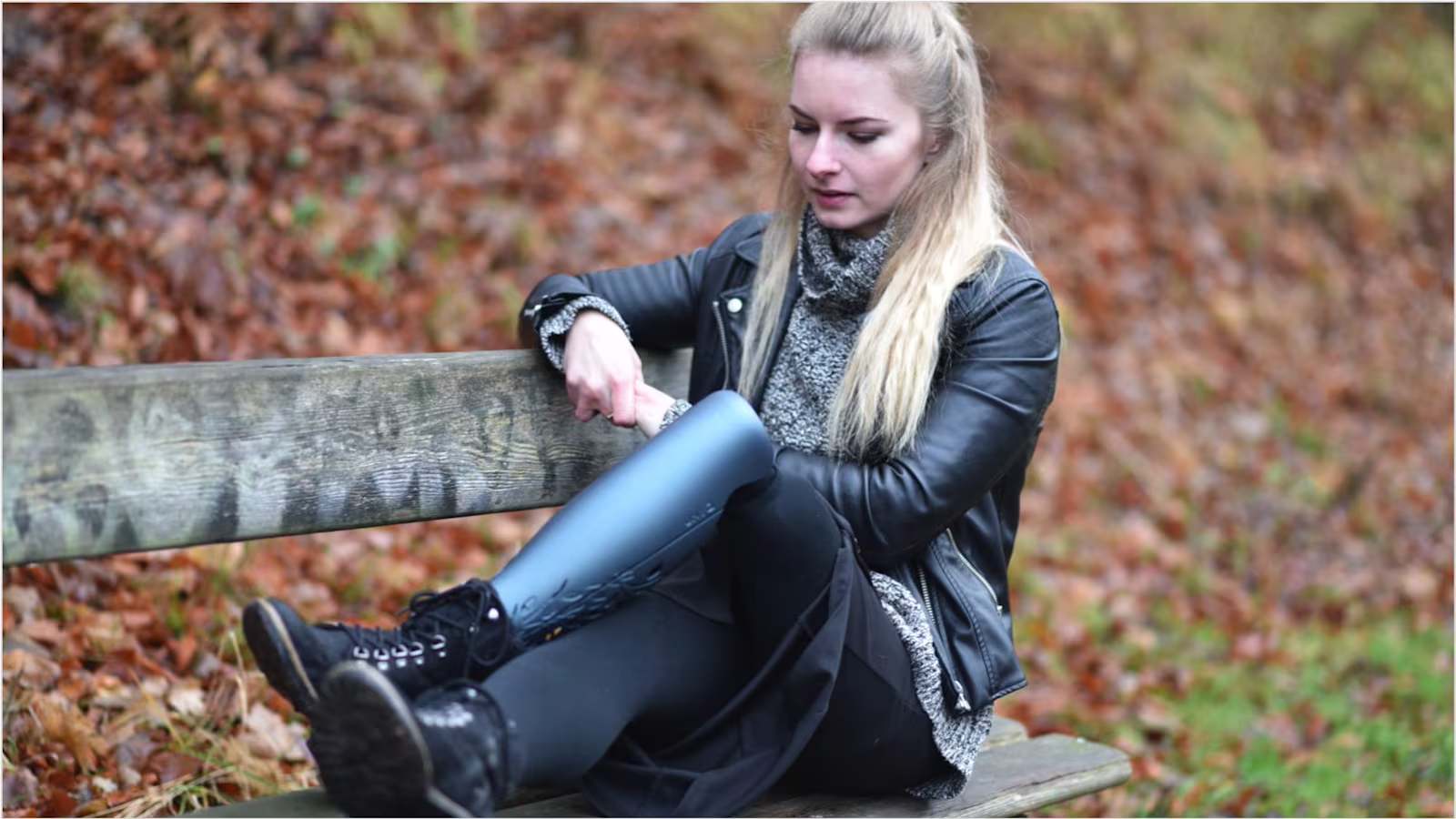 Girl wearing a grey prosthetic cover sitting on a wooden bench
