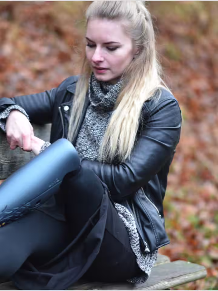 Girl wearing a grey prosthetic cover sitting on a wooden bench