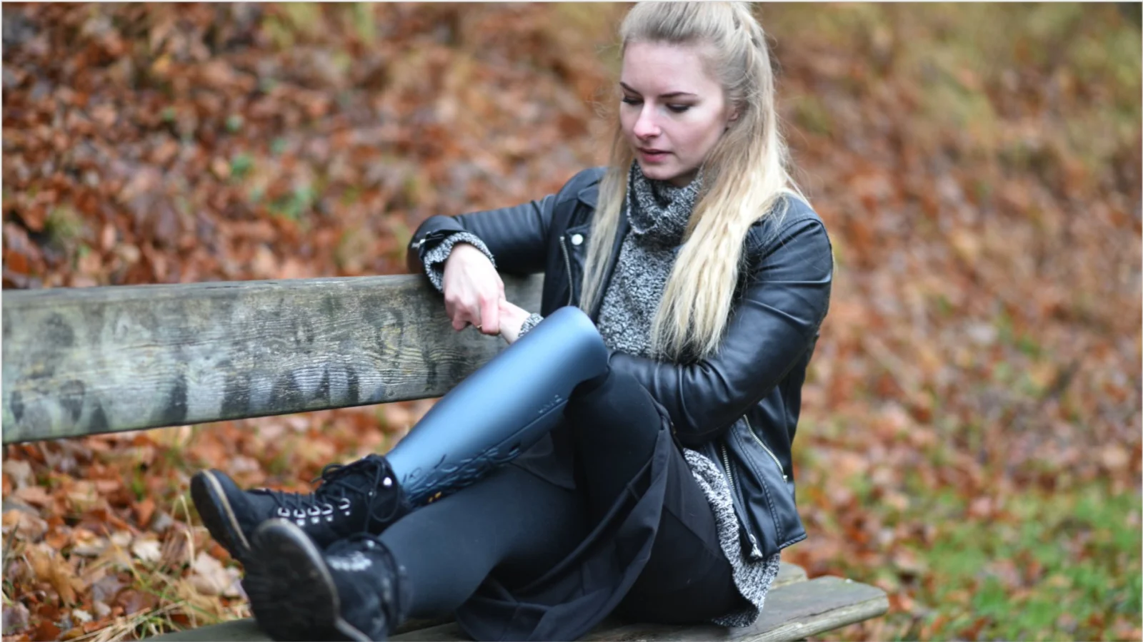 Girl wearing a grey prosthetic cover sitting on a wooden bench