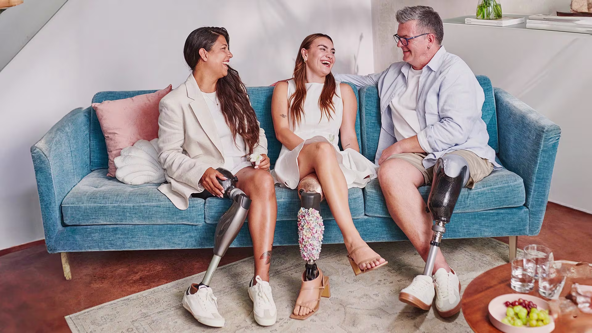 Three amputees wearing Ottobock prosthesis sitting on a couch while talking and laughing.