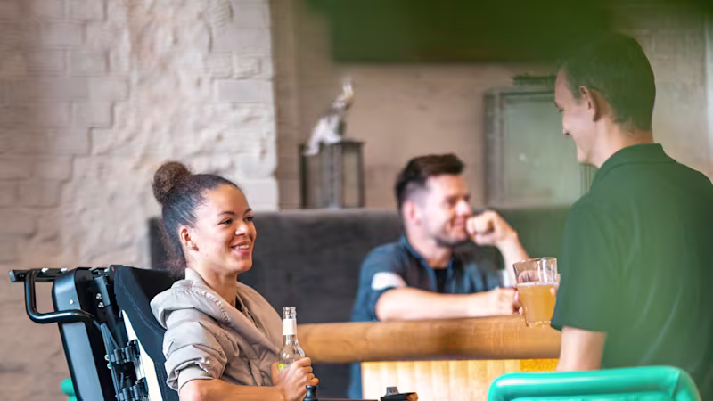 Juvo B7 user Elisa sitting in her Juvo B7 in a bar holding a beverage.