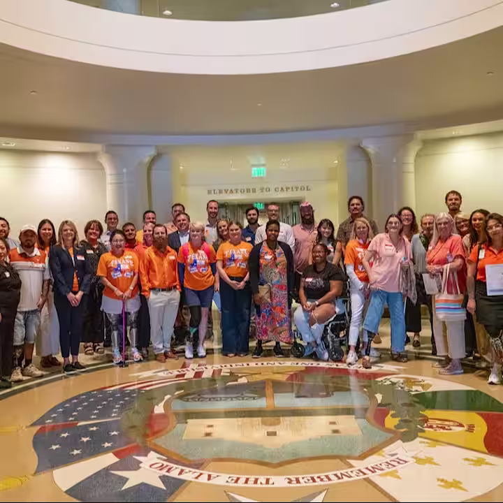 A group of the limb loss and limb difference community, Ottobock and Hanger professionals, and advocates posing in the Austin Capitol Building for Advocacy Day in Austin, TX
