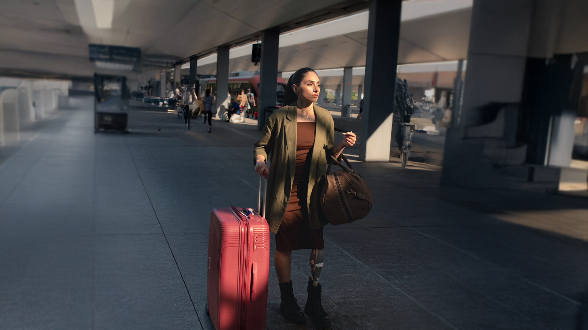 Mujer con una pierna protésica caminando con confianza por un aeropuerto con una maleta roja, presentada en la campaña Invisible Class de Ottobock sobre barreras de viaje y accesibilidad para personas con discapacidad.
