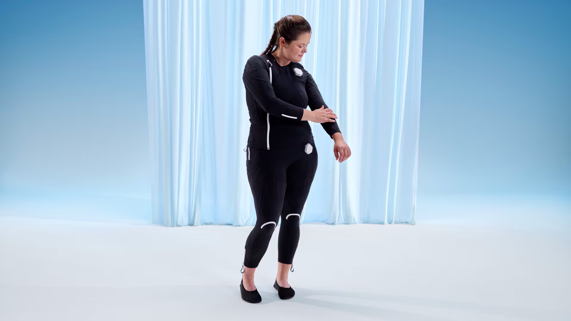 Ottobock user Lena touches her left arm wearing the exopulse suit.