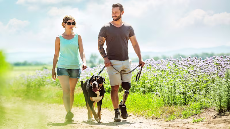 Un uomo che indossa una C-Leg 4 porta a spasso il suo cane accanto a una donna