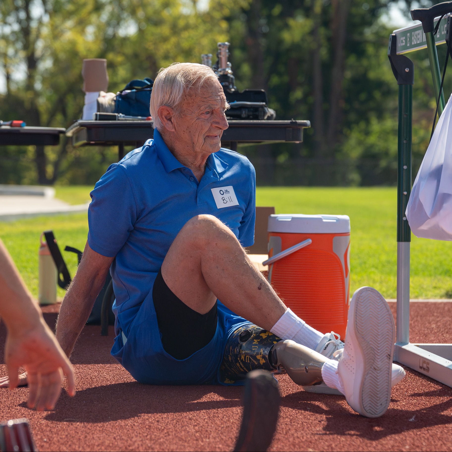 Un utilisateur âgé d’une prothèse de jambe s’étire sur une piste de course extérieure pour s’échauffer pour le Full Circle Movement