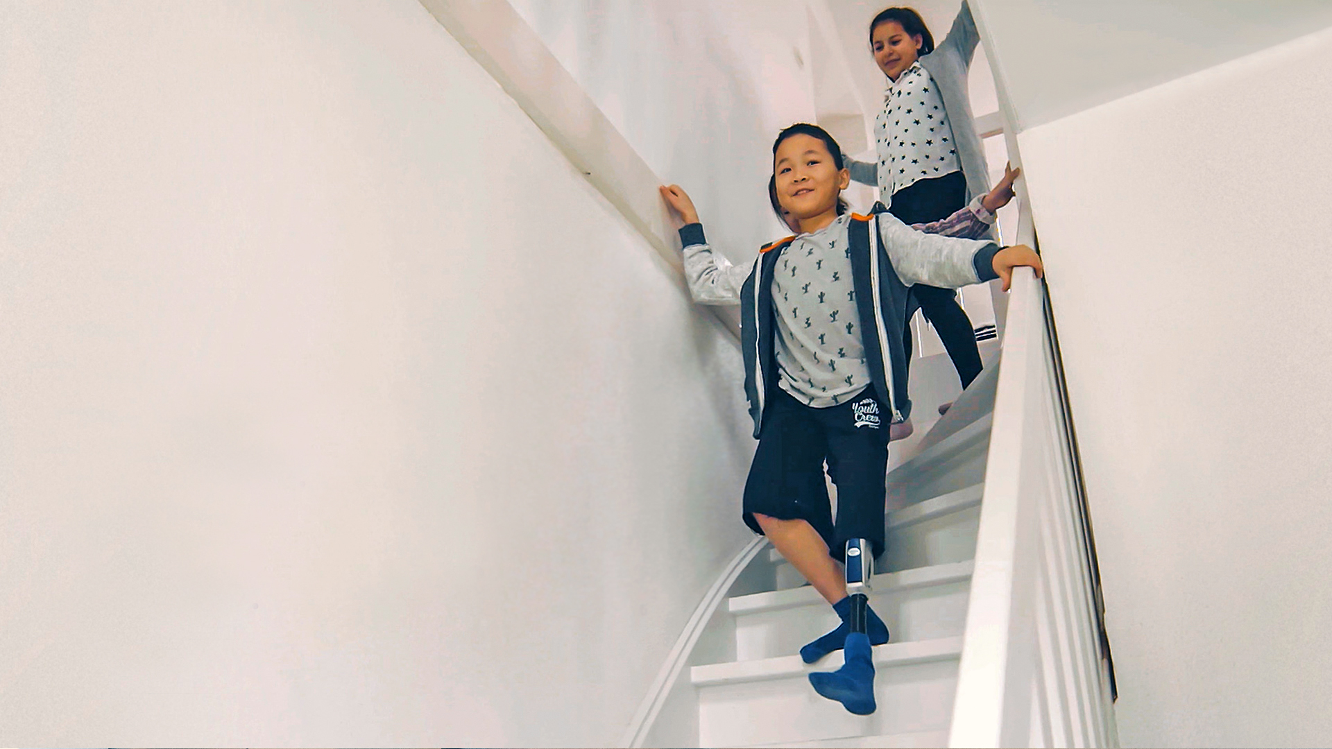 Ein kleiner Junge mit Prothesenkniegelenk läuft eine Treppe herunter.