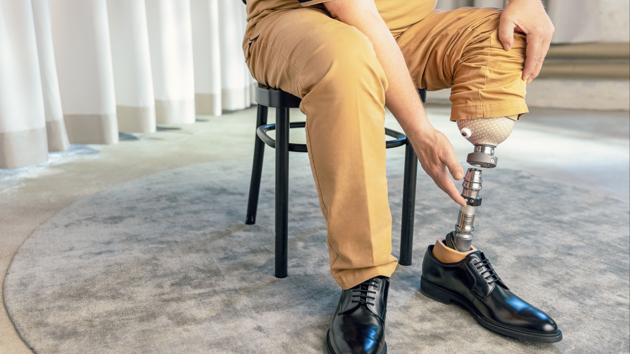 Person sitting on a stool connecting Ottobock Quickchange adapter to the Trias prosthetic foot
