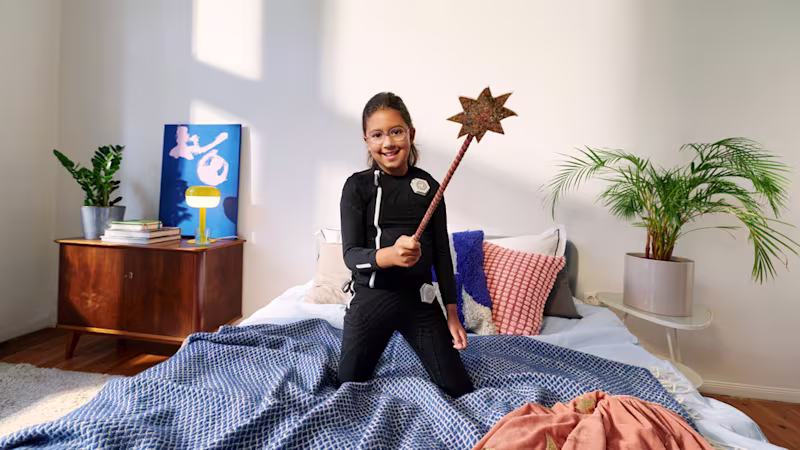 Child wearing the exopulse suit for children while seated on a bed