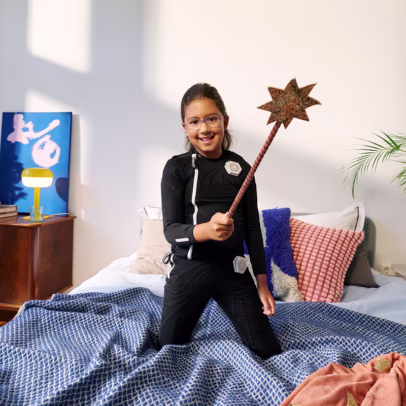 Child wearing the exopulse suit for children while seated on a bed