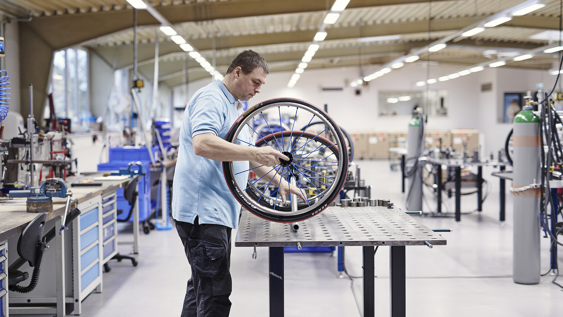 Wheelchair technician in a workshop holding a sports wheelchair tire on a workbench