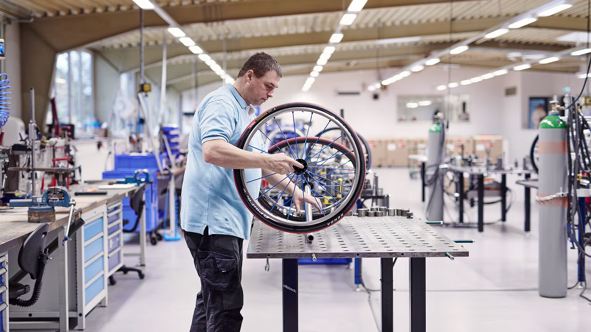 Wheelchair technician in a workshop holding a sports wheelchair tire on a workbench