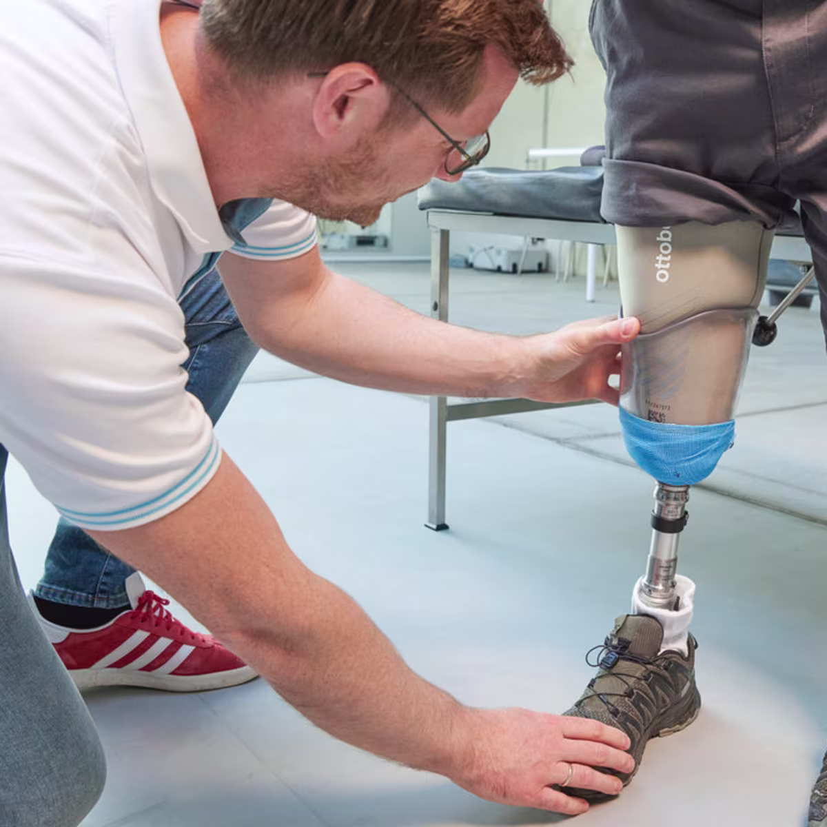 Ein Orthopädietechniker kniet auf dem Boden und justiert einen MyFit TT Schaft von Ottobock bei einem amputierten Mann.