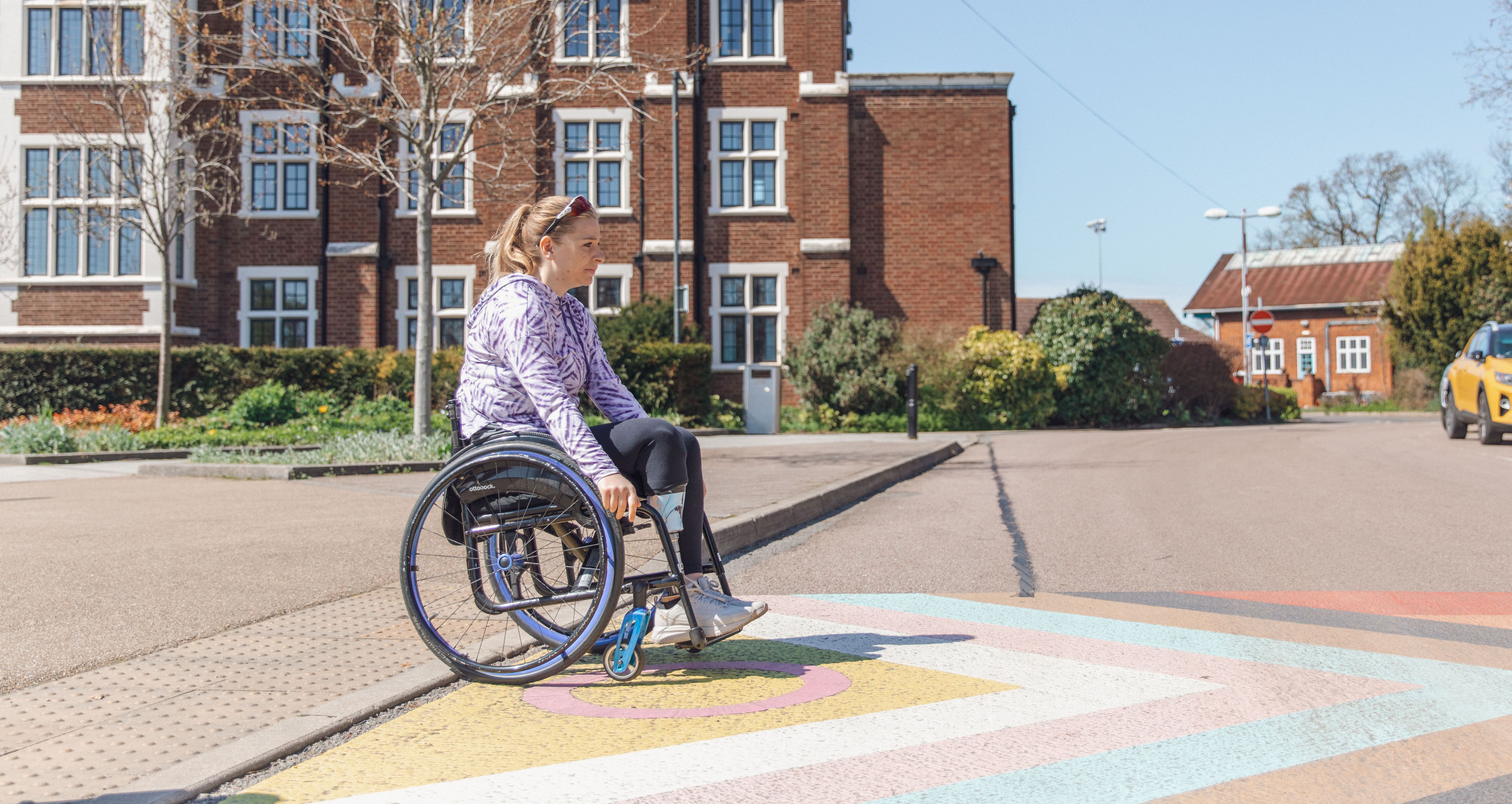 Hannah Moore in her Avantgarde lightweight manual wheelchair self-propelling across a street