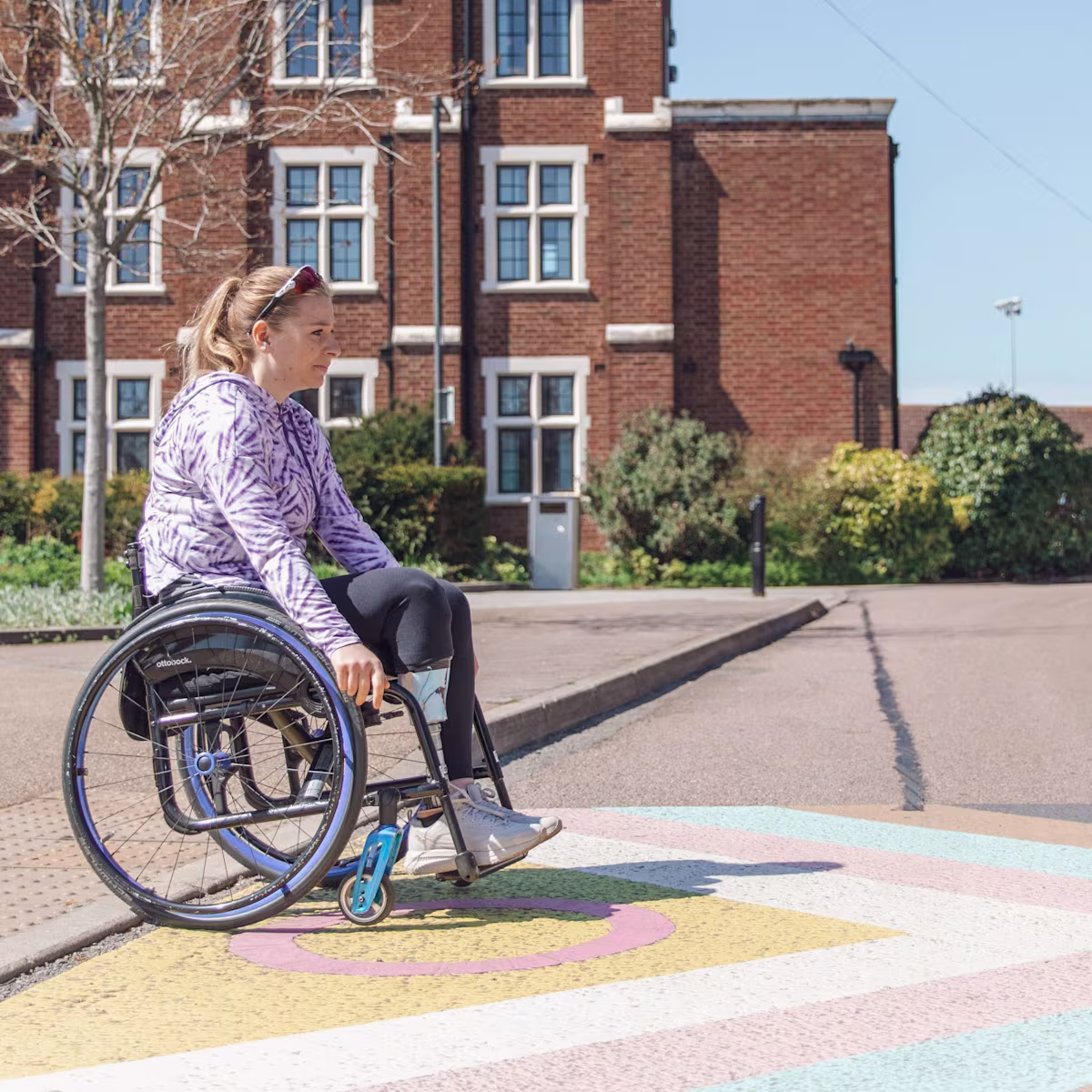 Hannah Moore in her Avantgarde lightweight manual wheelchair self-propelling across a street