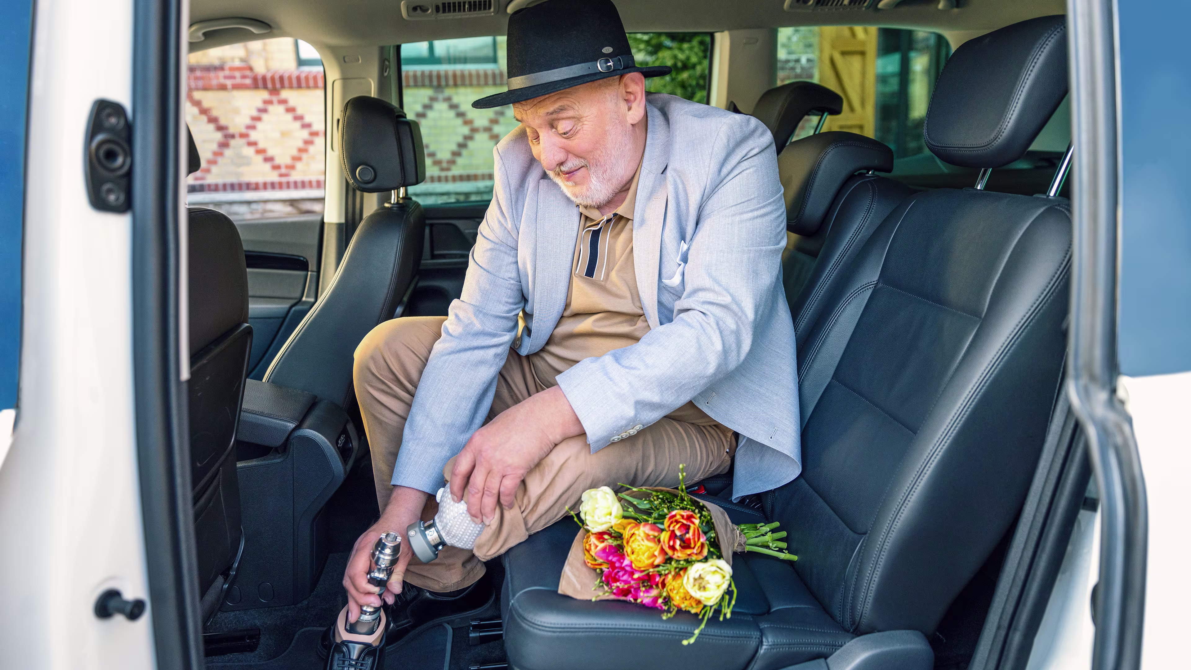 Ein älterer Mann sitzt im Auto und entfernt mittels des Quickchange Adapters von Ottobock seinen Prothesenfuß vom Schaft.