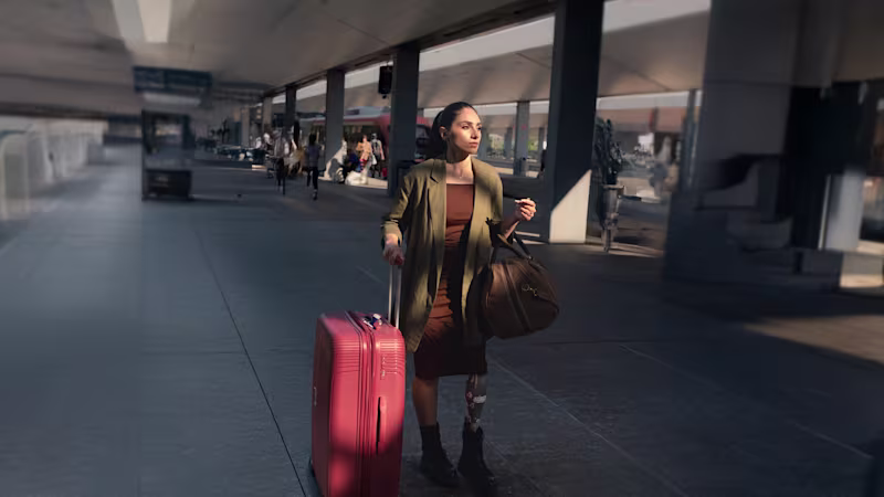 Woman with a prosthetic leg walking confidently through an airport with a red suitcase, featured in Ottobock’s Invisible Class campaign about travel barriers and accessibility for people with disabilities.